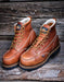 Pair of brown leather boots with laces on a wooden surface