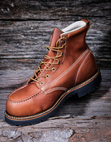 Brown leather boot with gold laces on a wooden background