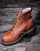 Brown leather boot with gold laces on a wooden background