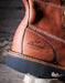 Close-up of a brown leather boot with 'Thorogood' logo on a wooden block.