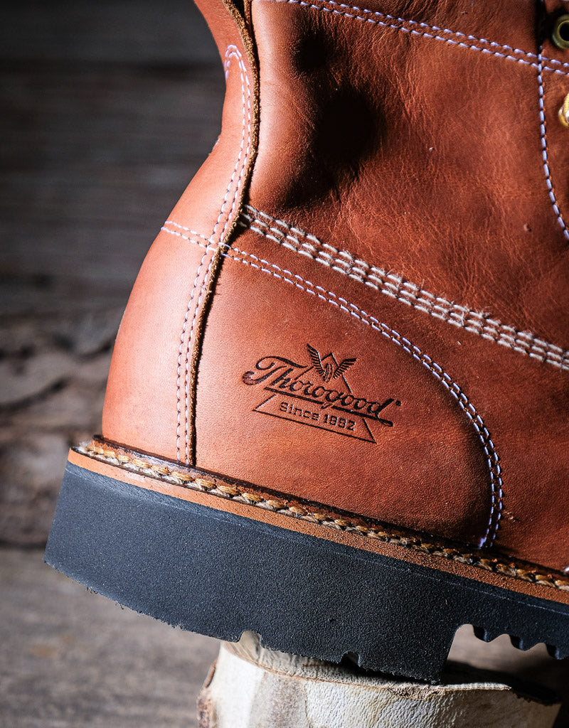 Close-up of a brown leather boot with 'Thorogood' logo on a wooden block.