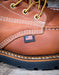 Close-up of a brown leather boot with American flag label on a wooden surface