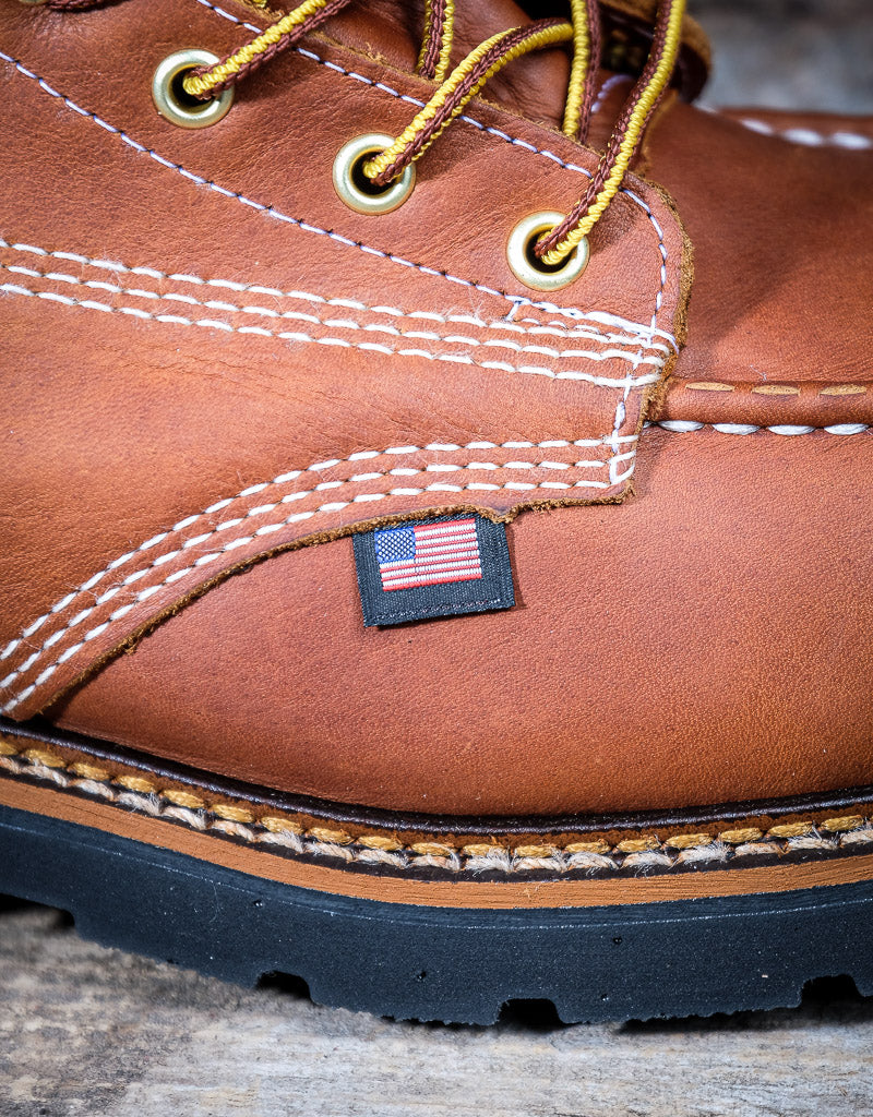 Close-up of a brown leather boot with American flag label on a wooden surface