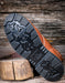 Brown leather boot with black sole on a wooden background