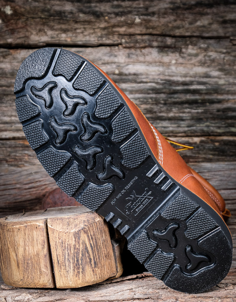 Brown leather boot with black sole on a wooden background