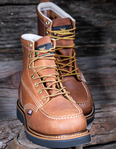 Pair of brown leather boots with yellow laces on a wooden surface