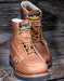 Pair of brown leather boots with yellow laces on a wooden surface