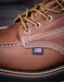 Close-up of a brown leather boot with American flag label on a dark background