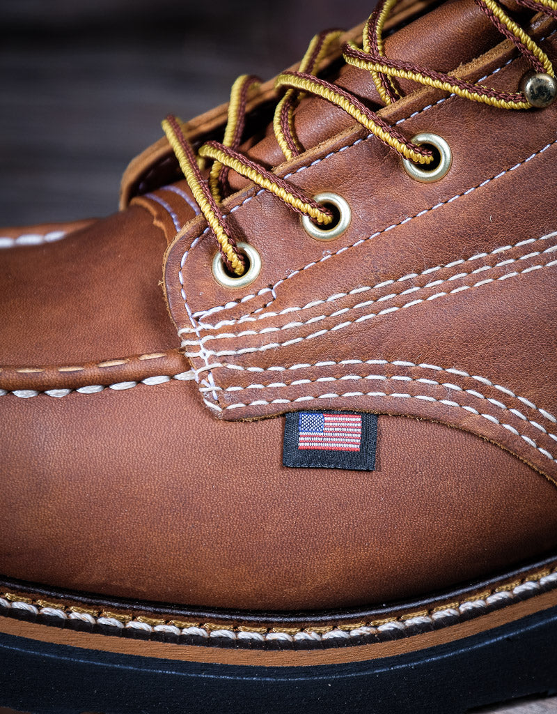 Close-up of a brown leather boot with American flag label on a dark background