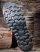 Close-up of a shoe sole with tread pattern on a wooden background