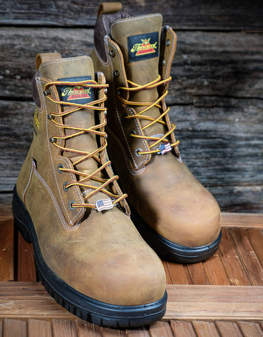 Pair of brown work boots with Thorogood brand labels on a wooden surface