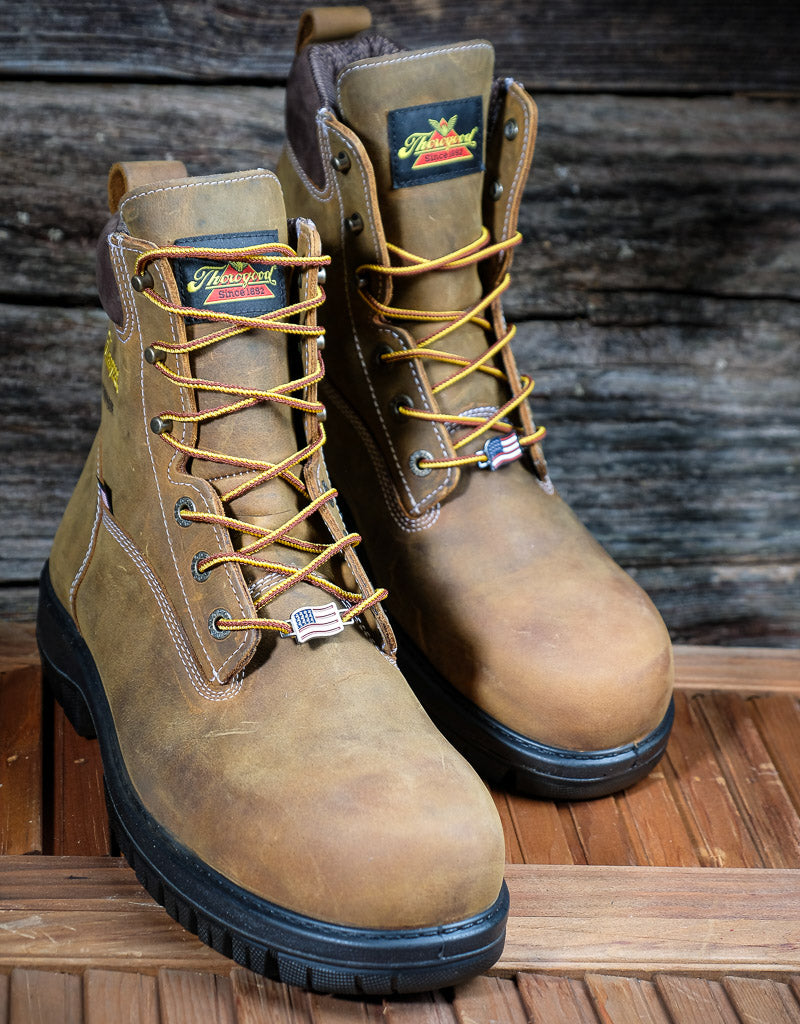 Pair of brown work boots with Thorogood brand labels on a wooden surface