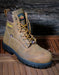 Brown work boot with black sole on a wooden surface