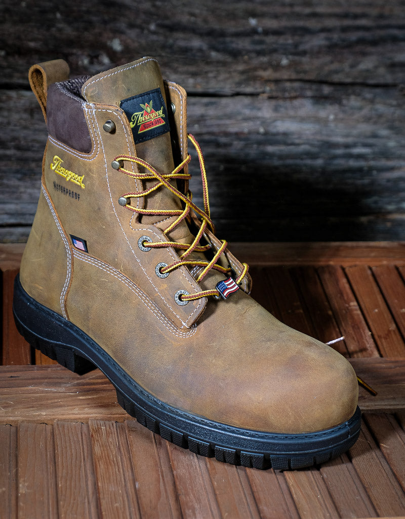 Brown work boot with black sole on a wooden surface