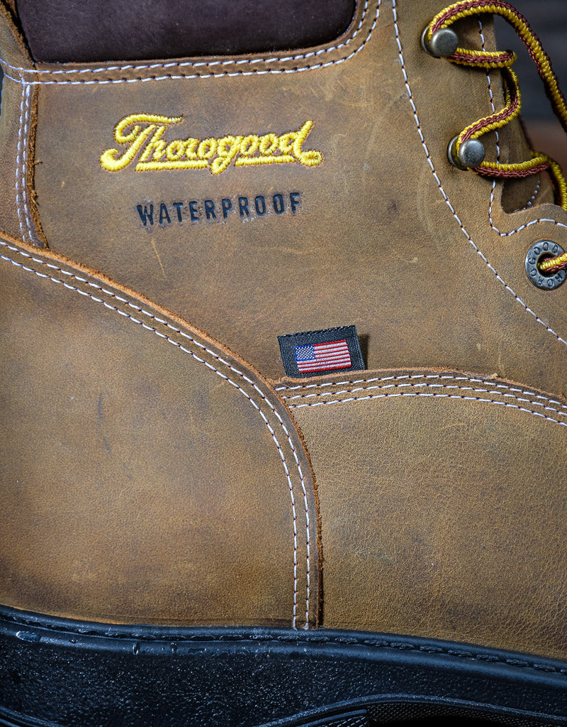 Close-up of a brown leather boot with 'Thorogood' branding and waterproof label. And small American flag label