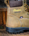 Brown work boot with 'Thorogood' branding on a wooden surface