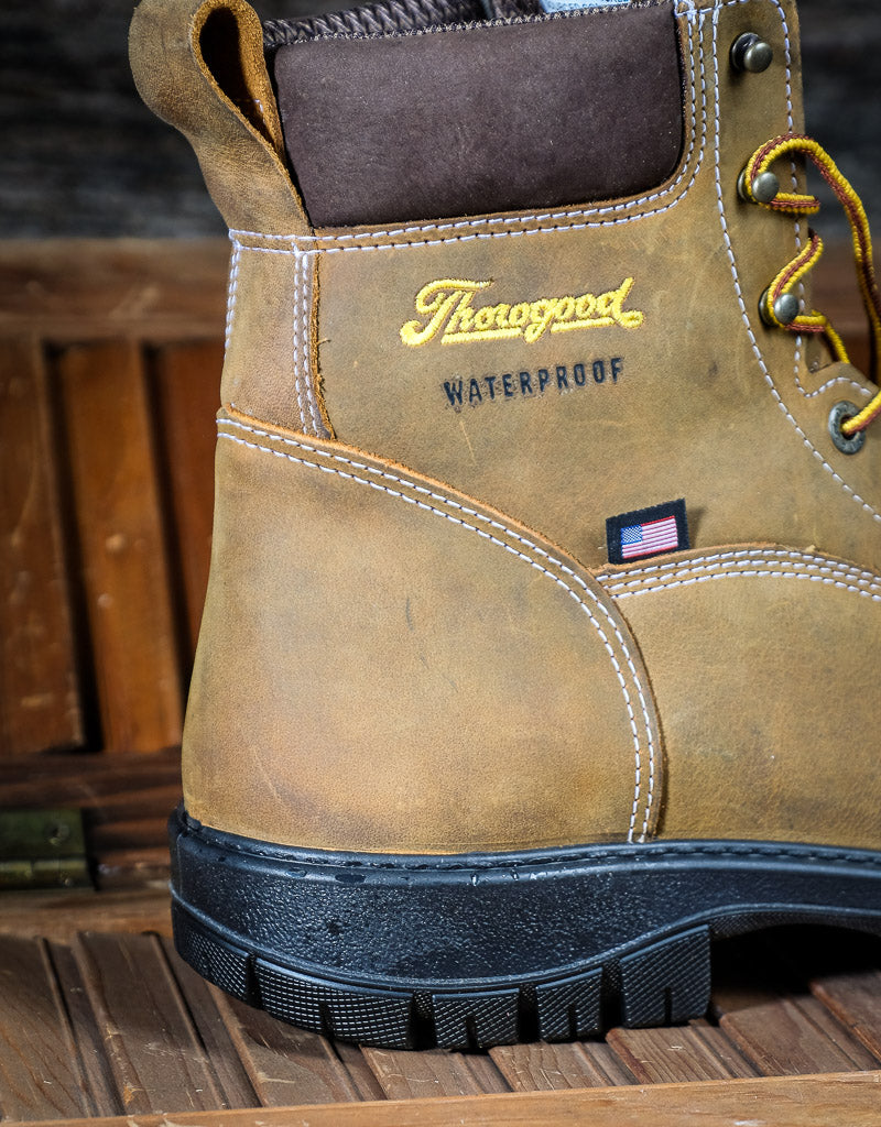 Brown work boot with 'Thorogood' branding on a wooden surface