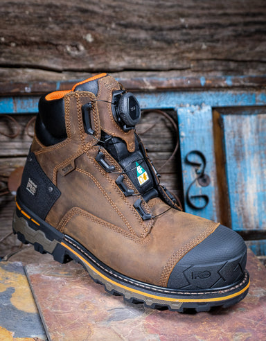 Brown work boot with black sole on a rustic wooden background