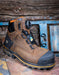 Brown work boot with black sole on a rustic wooden background