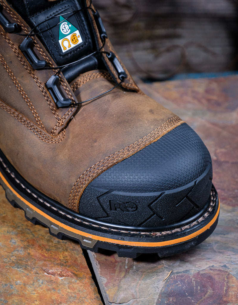 Brown work boot with black toe cap on a textured surface