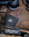 Close-up of a brown leather boot with a label that says 'Waterproof' and 'Timberland PRO composite toe' on a wooden surface.
