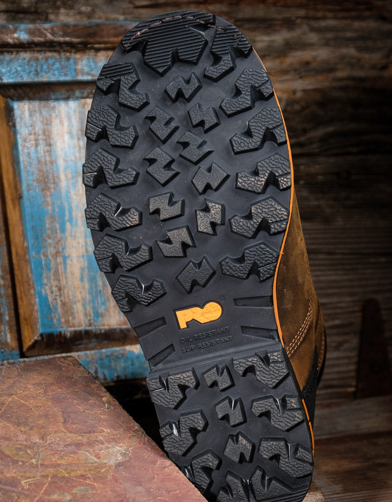 Close-up of a brown leather shoe sole with rugged tread pattern on a wooden surface