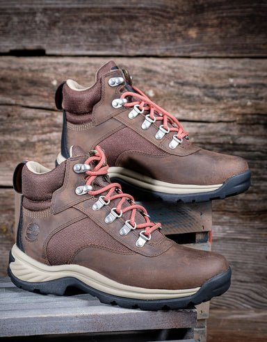 Pair of brown hiking boots with coral laces on a wooden background