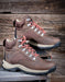 Pair of brown hiking boots with coral laces on a wooden background