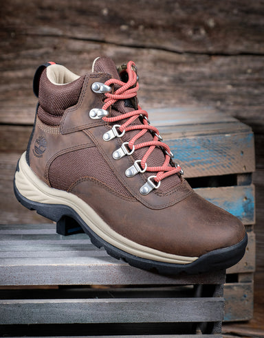 Brown hiking boot with pink laces on a wooden pallet