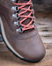 Brown hiking boot with pink laces on a wooden surface