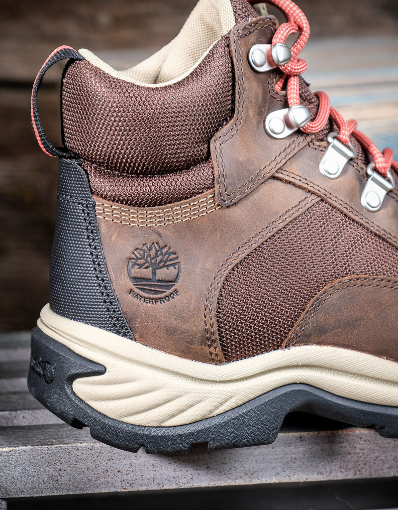 Brown hiking boot with visible Timberland logo and waterproof stamp on a wooden surface