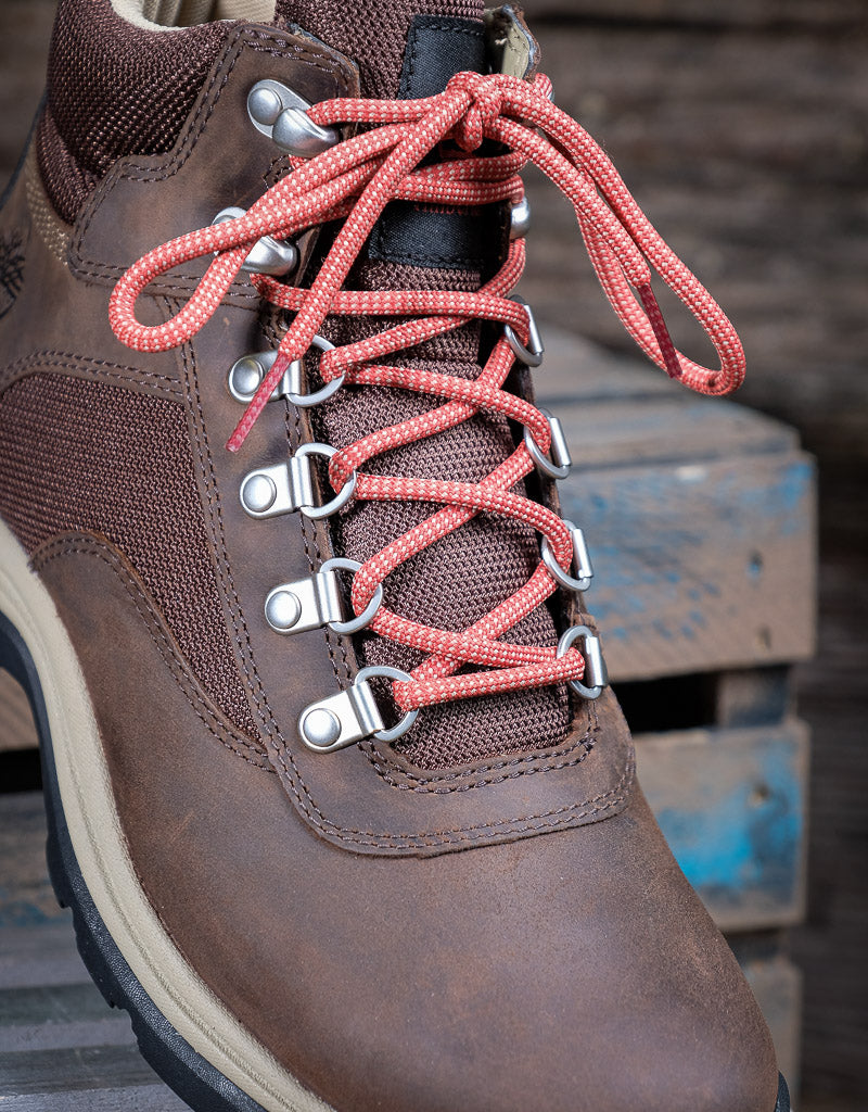 Close-up of a brown boot with red laces on a blurred background