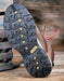 Close-up of a shoe sole with a detailed tread on a wooden surface
