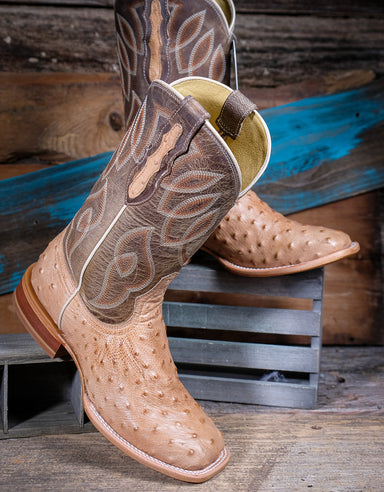 Pair of tan and brown cowboy boots with detailed design on a wooden background