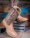 Pair of tan and brown cowboy boots with detailed design on a wooden background