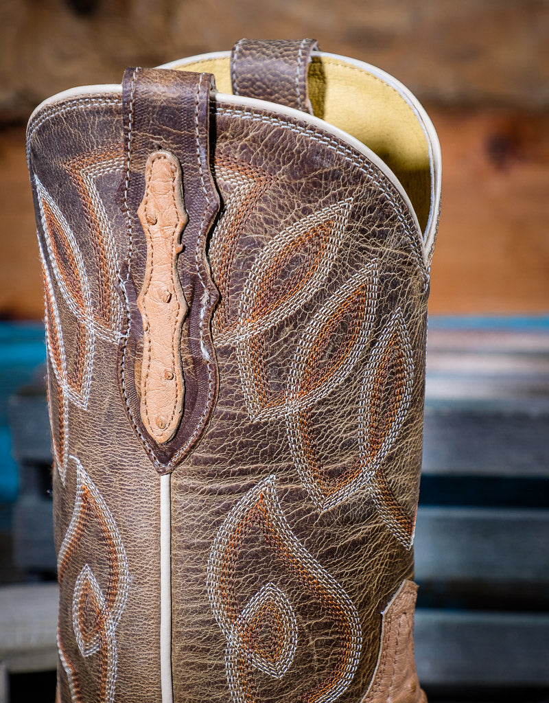 Close-up of a brown leather boot with intricate western stitching and design.