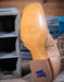 Close-up of a cowboy boot sole with Tony Lama branding on a wooden surface.