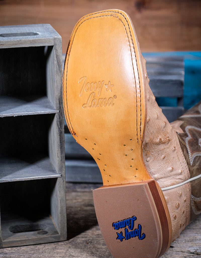 Close-up of a cowboy boot sole with Tony Lama branding on a wooden surface.
