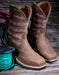 Pair of brown cowboy boots with barbed wire design on a wooden surface with a spool of green thread.