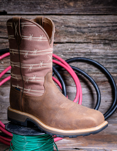 Brown cowboy boot with barbed wire pattern on a wooden surface with coiled hoses.
