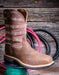 Brown cowboy boot with barbed wire pattern on a wooden surface with coiled hoses.