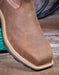 Brown leather boot on a wooden surface with green wire in the background