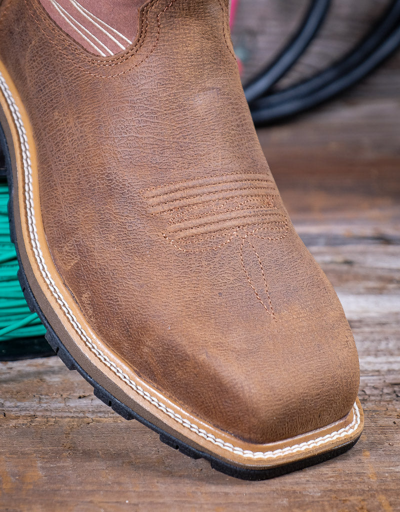 Brown leather boot on a wooden surface with green wire in the background