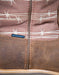 Close-up of a brown leather boot with barbed wire pattern and waterproof label.