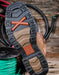 Close-up of a boot sole with a Twisted X brand logo on a wooden surface with cables.