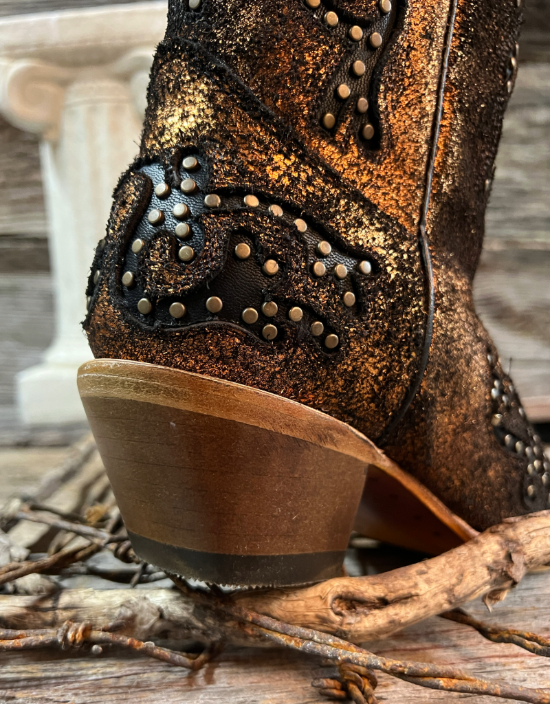 Close-up of a cowboy boot heel with intricate stitching and studs on a wooden surface.