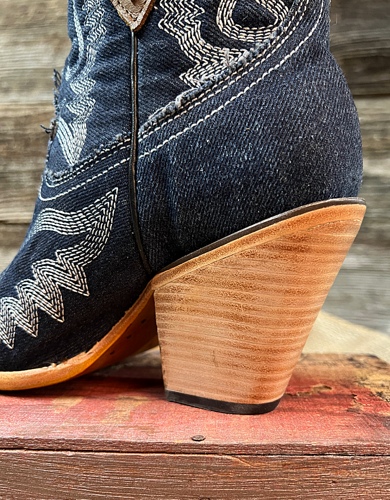 Closeup on wooden stacked heel of blue western boot sitting on top of a red wooden box