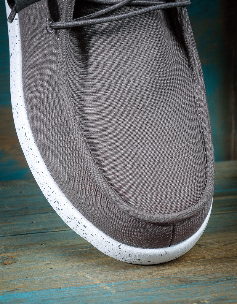 A close up of the toe of a shoe, the shoe is grey with a white sole