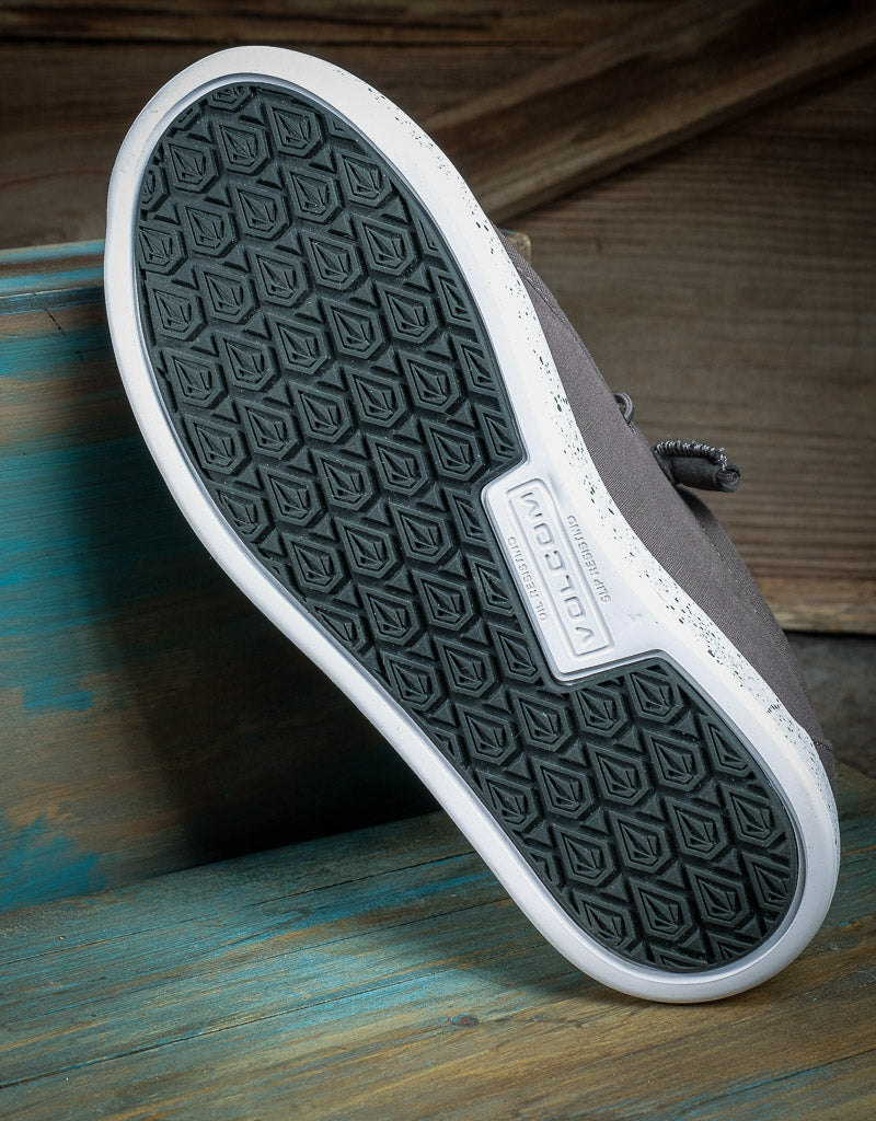 View of the bottom of a shoe. The sole pattern is white and black with a Volcom emblem
