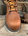 Brown leather boot toe with a white sole on a rustic wooden background